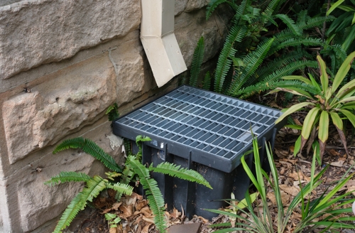 Downspout drainage system on a sandstone wall | Conserva Irrigation