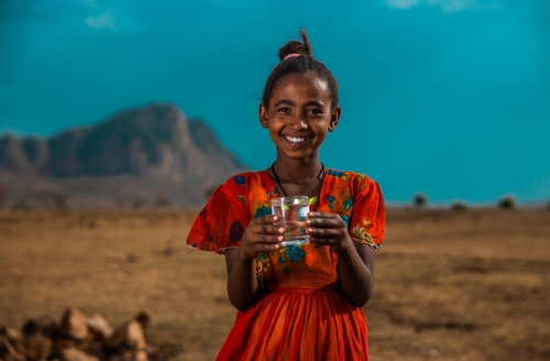 Ethiopian girl holding a glass of water in the desert | Conserva Irrigation
