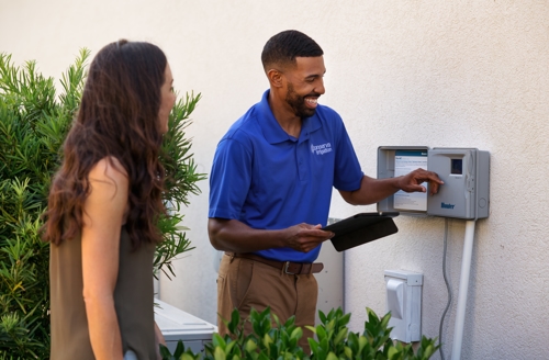 A Conserva Irrigation technician showing a homeowner how to program their Hunter Hydrawise Smart Controller.