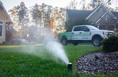sprinkler running on lawn with Conserva truck parked behind it