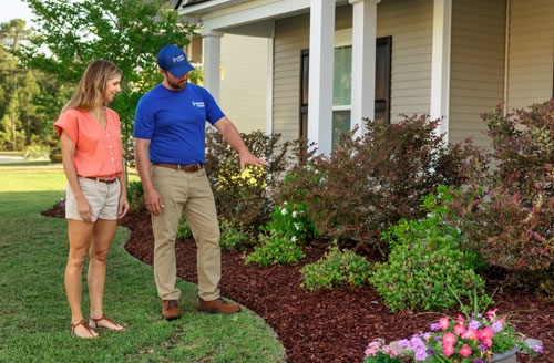man talking to woman about flower bed