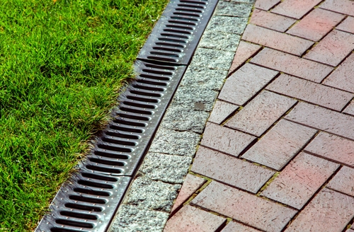 iron drainage net between paving slab and green lawn.
