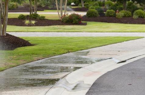 Sprinklers running on sidewalk