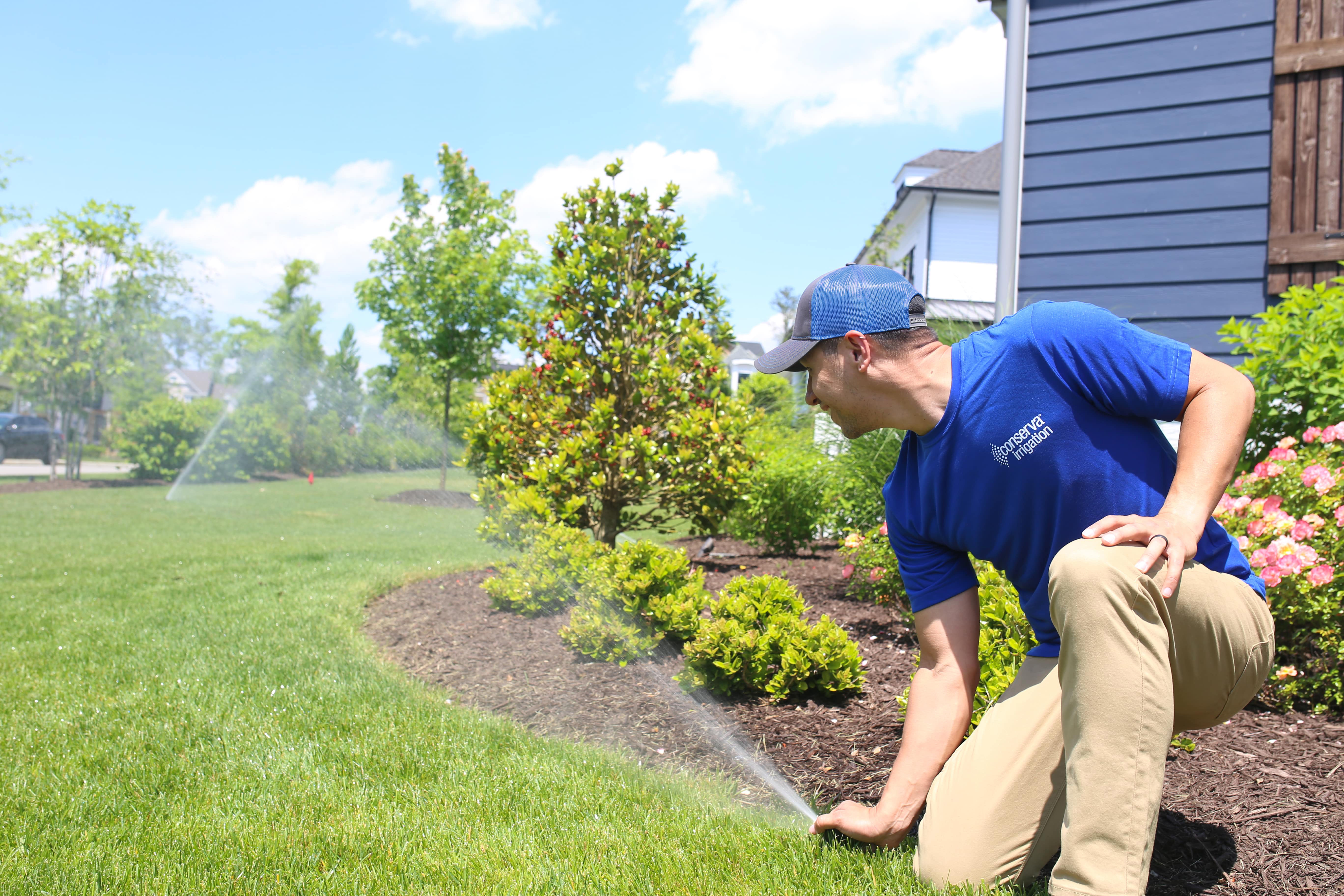 Conserva Irrigation repair specialist inspecting sprinklers in residential front yard
