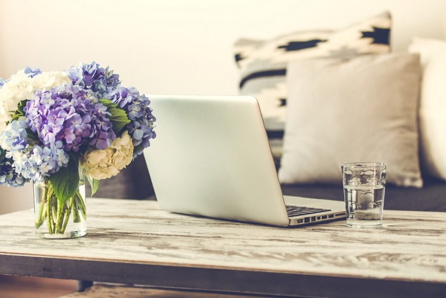 stock image of flower laptop and cup on a coffee table