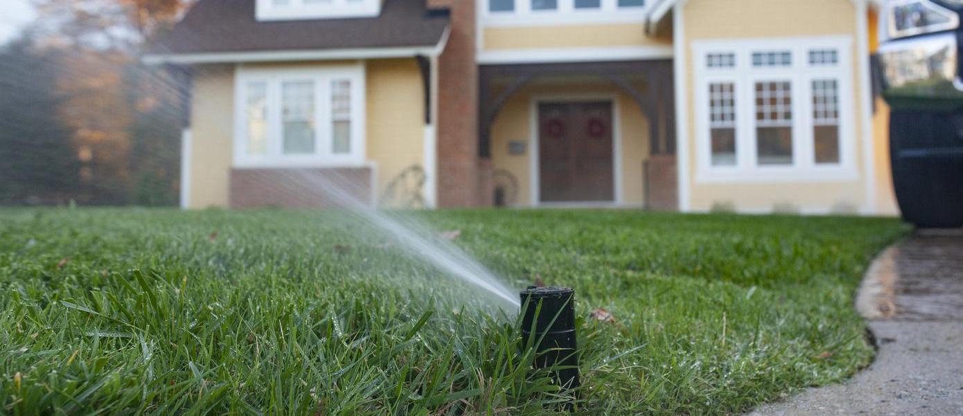 sprinklers in front of a yellow house
